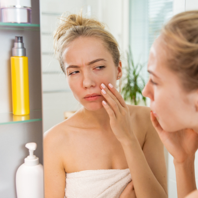 Woman inspecting skin in mirror