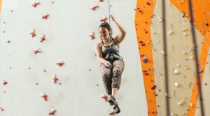 Woman descending from an indoor climbing facade tied to a harness
