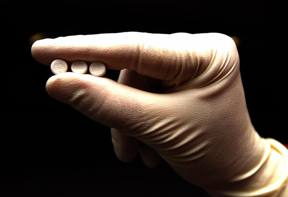 A gloved hand holds three MDMA tablets, more commonly known as Ecstasy.